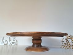 a wooden cake plate sitting on top of a table next to some cut out letters