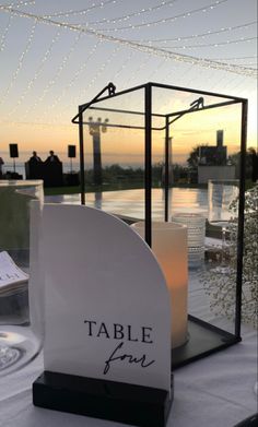 a table with a candle and sign that says table for two in front of the water