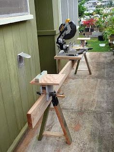 a table sawing on top of a wooden bench in front of a building with green siding