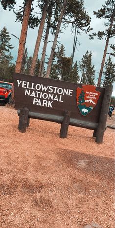 the yellow stone national park sign is in front of some pine trees and other vehicles