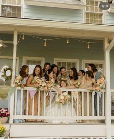 a group of women standing on top of a porch next to each other holding bouquets