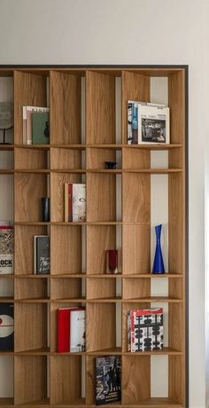 a wooden book shelf with many books on it's sides and two blue vases in the middle