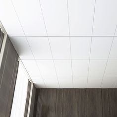 an empty room with wood paneling and white ceiling tiles