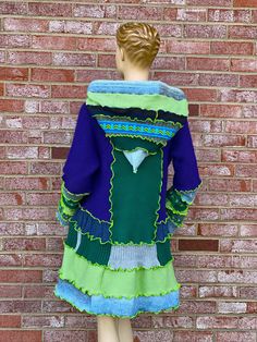 a mannequin is standing in front of a brick wall wearing a green and blue dress