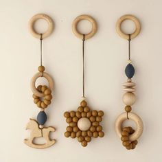 three wooden toys are hanging from hooks on the wall, with beads and rings attached to them