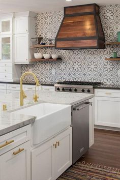 a kitchen with white cabinets and gold accents