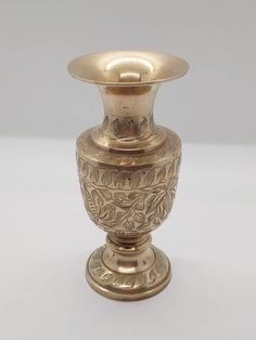 an antique brass vase is sitting on a white surface