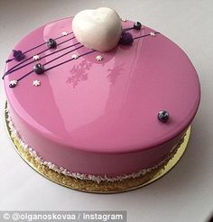 a pink cake with white frosting and music notes on top, sitting on a gold plate