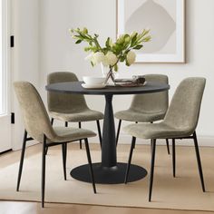 a dining room table with four chairs around it and a vase on top of the table