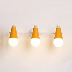 three orange cones are hanging on the wall next to two white lights and one yellow light