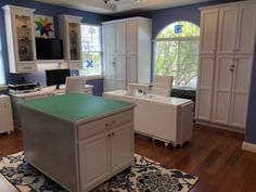 an office with blue walls and white cabinets is pictured in this image, there are two desks on either side of the room