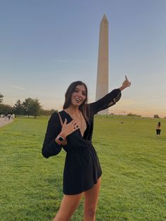 a woman posing in front of the washington monument with her hand up to the sky