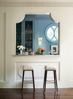 two stools in front of a bar with a mirror on the wall above it