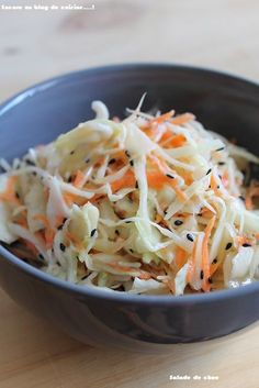 a bowl filled with coleslaw and carrots on top of a wooden table