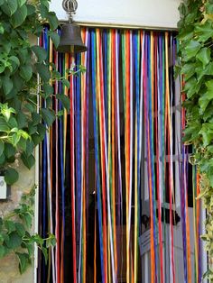 an open door with colorful streamers hanging from it's side and green plants growing on the outside