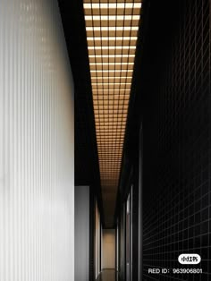 an empty hallway with white walls and black tiles on the floor is lit by a light fixture