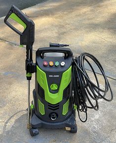 a green and black electric pressurer on the ground with hoses attached to it