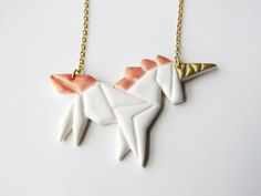 two white and pink unicorn necklaces on a gold plated chain, one is shaped like an origami