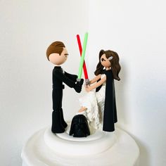 a star wars wedding cake topper with a bride and groom holding lightsabens