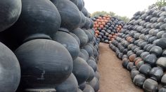 large piles of black and orange vases sitting next to each other on the ground