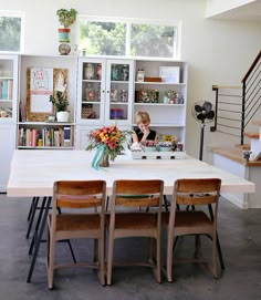 a woman sitting at a table in front of a book shelf filled with lots of books