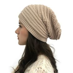 a woman with long hair wearing a knitted beanie in light brown, standing against a white background