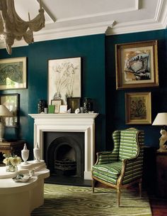 a living room filled with furniture and paintings on the wall above a fire place in front of a fireplace