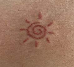 the back of a person's neck with a sun tattoo on it and red ink