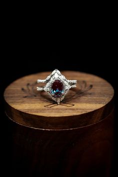 a diamond and blue topazte ring sitting on a wooden stand in front of a black background