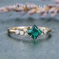 an emerald colored ring with three diamonds on it