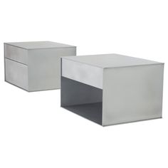 two silver side tables sitting next to each other on a white background, one is empty and the other has an open drawer