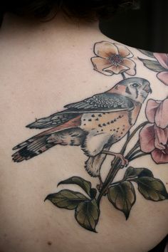 a woman's back with a bird and flowers on it