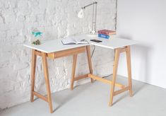 a desk with a book and lamp on it next to a white brick wall in an empty room