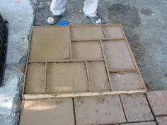 a person standing on top of a sidewalk next to a cement slab with squares cut into it