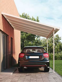 a black car parked in front of a brick building with a white awning over it