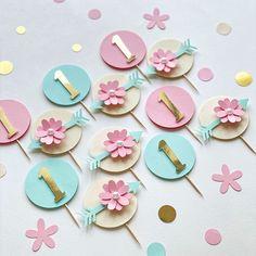 a table topped with pink and blue cupcakes covered in gold foiling next to confetti sticks