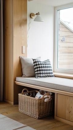 a window seat with two baskets under it and a pillow on the bench next to it