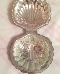 an antique silver shell shaped dish on a pink and white tablecloth