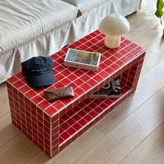 a red and white tiled coffee table with a cell phone, hat, and book on it