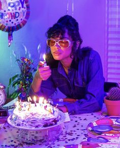 a woman sitting at a table in front of a birthday cake with candles on it