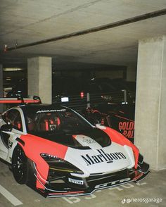 two race cars parked next to each other in a parking garage with no one around them