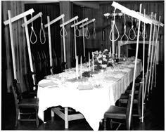 an old black and white photo of a long table with candles, flowers and scissors on it