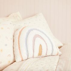 a close up of pillows on a bed with pink and white striped walls behind them