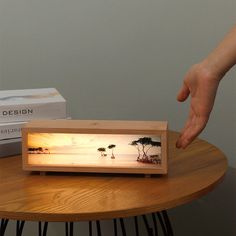 a person reaching for something on a table with a box in the background and a hand touching it