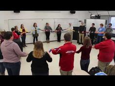 a group of people standing in a room holding onto some yellow and blue ribbones