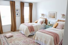 two beds in a bedroom with pink and white bedding