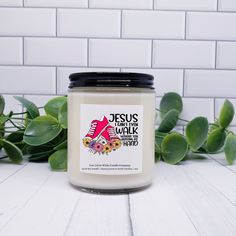 a candle sitting on top of a white table next to some green leaves and a brick wall