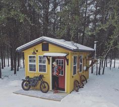 a small yellow cabin with a motorcycle parked outside