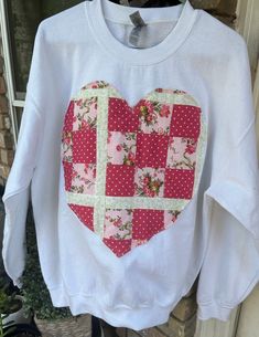 a white t - shirt with a heart patchwork on the chest and pink flowers