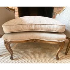 a chair and ottoman sitting next to each other in front of a fire place with a mirror